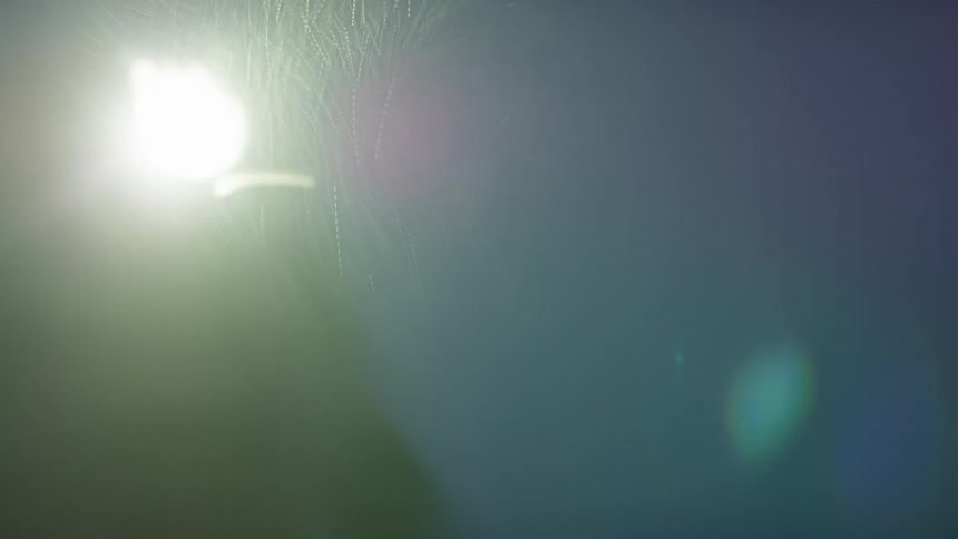 A person with a flashlight on their head looking around in the rain with the sky and clouds in the background