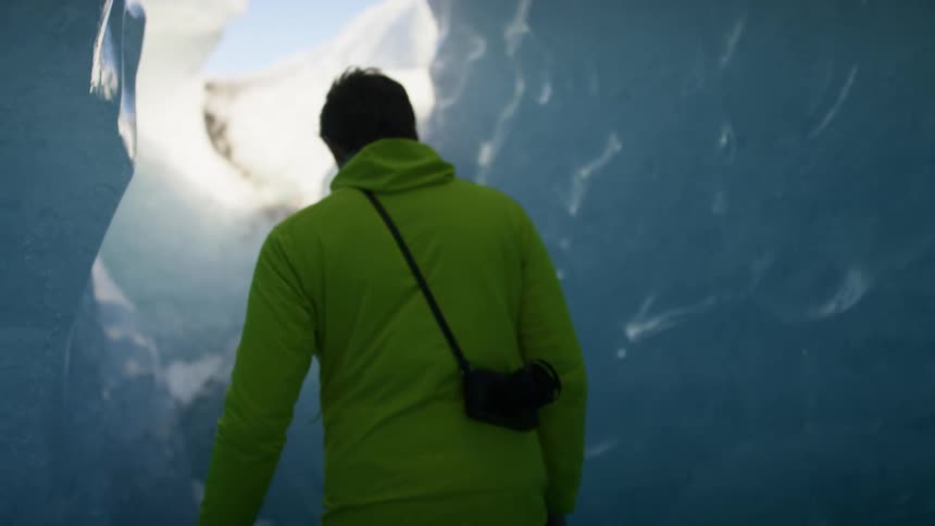 A man turns and walks towards an opening in a snow cave