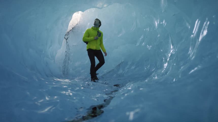 A man looks around as he walks through an ice cave
