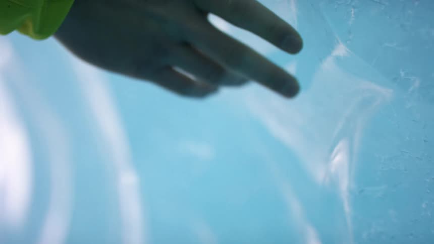 A person running their hand over a large chunk of ice