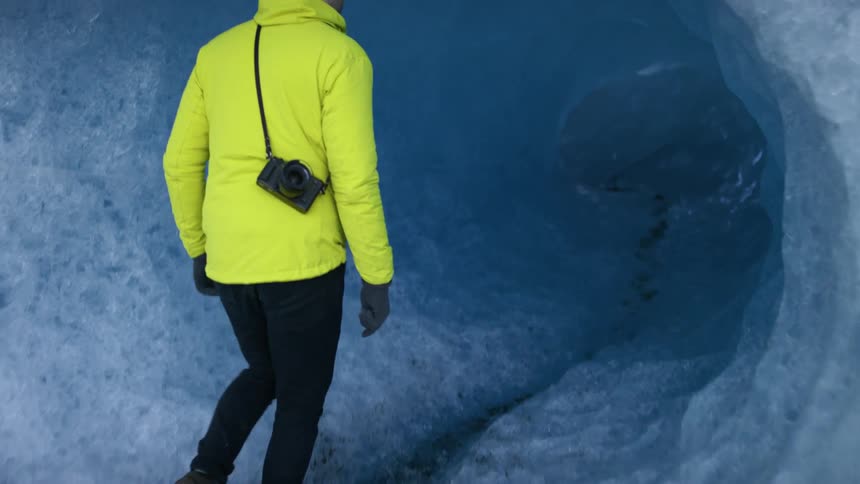 A man walks into a tunnel through a large mass of compacted snow and ice