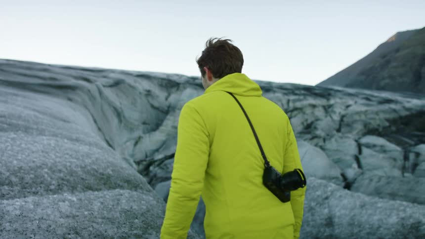 A man walks atop compacted ice in the mountains during the day