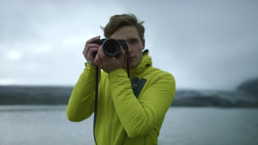 Man in bright green jacket aiming camera to take photo