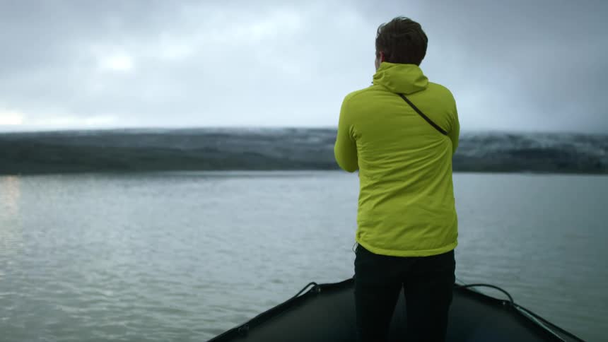 A man riding on a boat taking photos of some water
