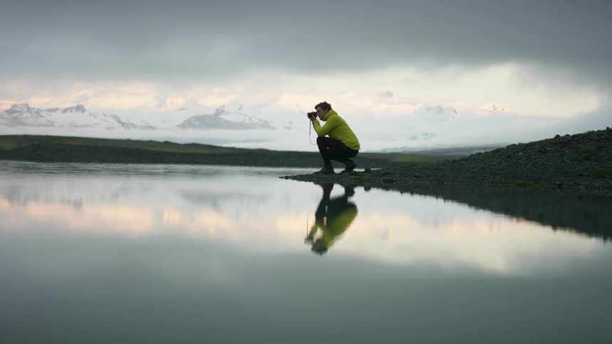 A man taking photos of a lake