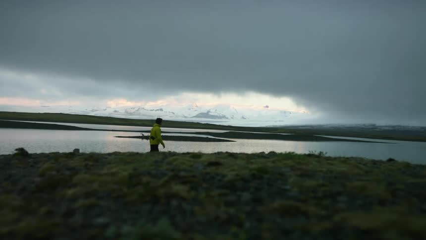 A man is walking past the water near the lake
