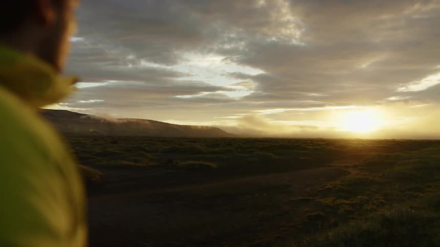 A photographer takes a photograph of a patchy grassland in the evening