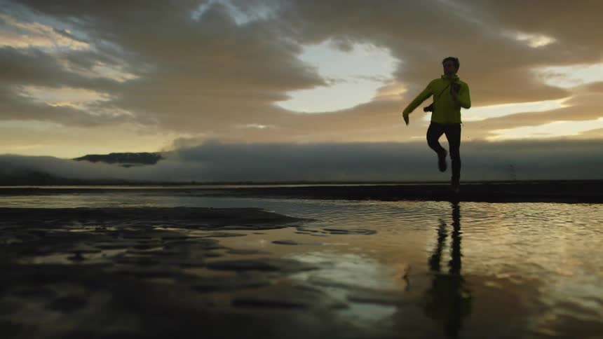 A man runs and jumps over the water on the beach