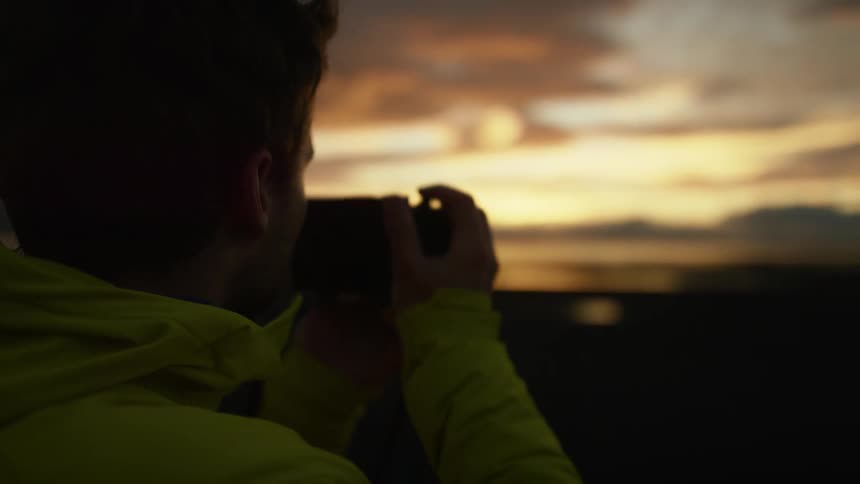 A man is taking a photograph at sunset