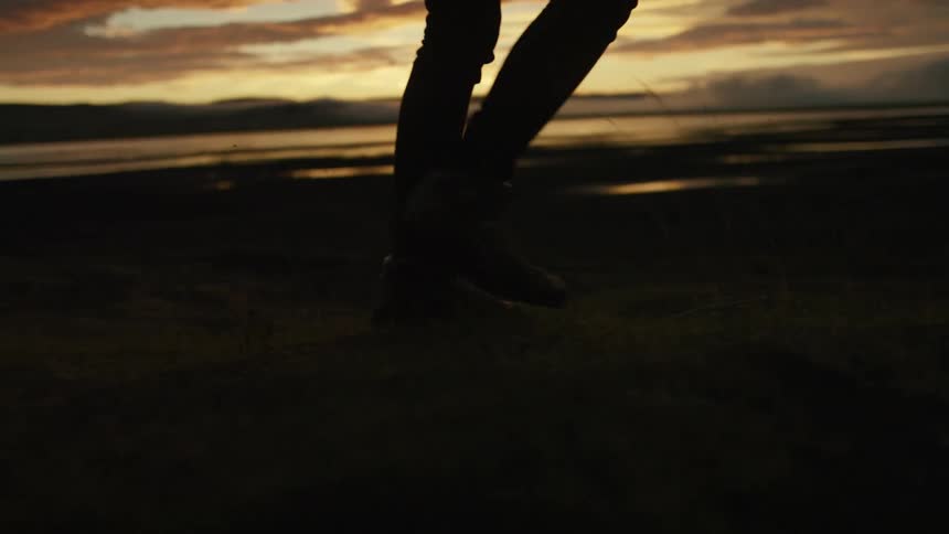 A man is walking outdoors at dusk by the beach