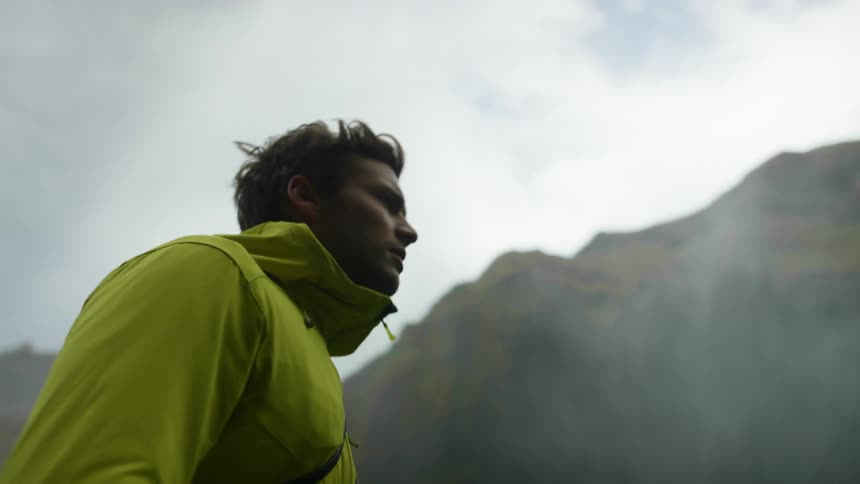 A man is walking outdoors next to the mountains