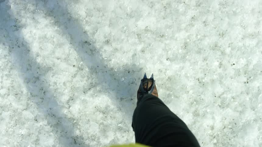 A person hiking over icy ground in snow cleats