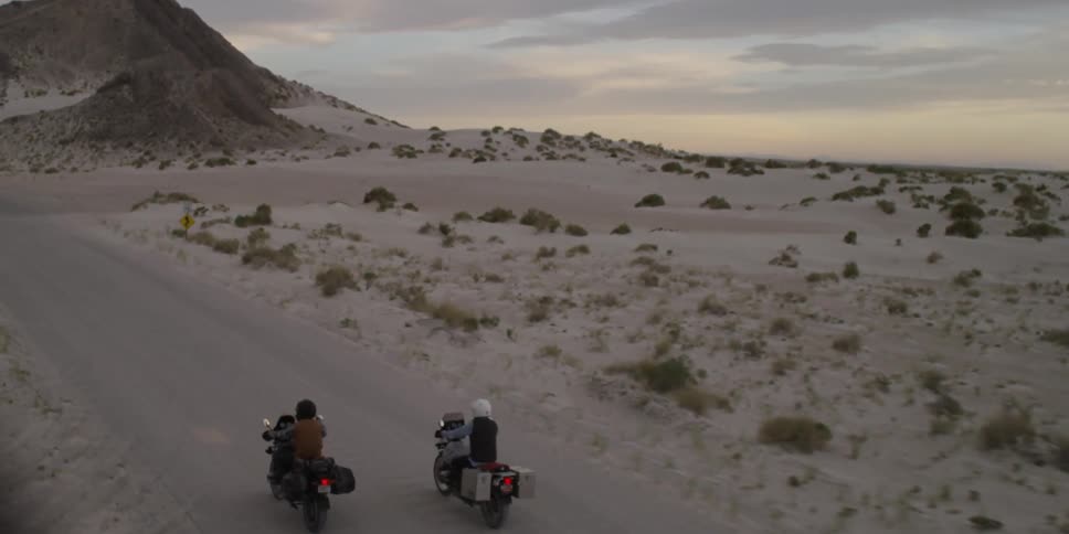 Motorcyclists ride on a road in the desert
