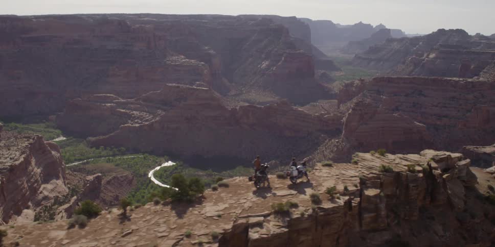 Aerial view moving over a cliff with two people looking over a cliff