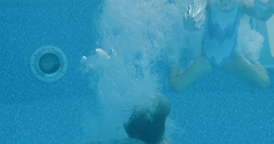 Two young girls jump into a swimming pool together