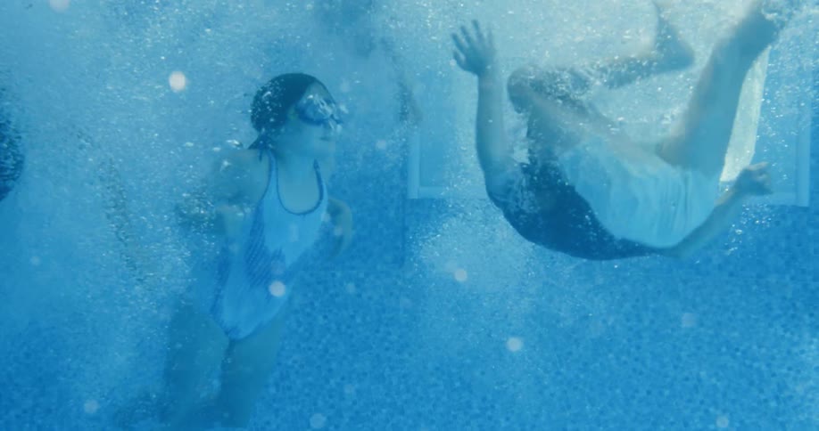 Children jump in the pool and swim underwater