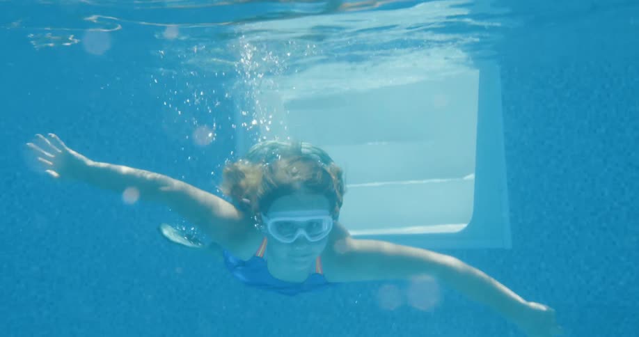 A little girl swimming underwater in a mermaid outfit