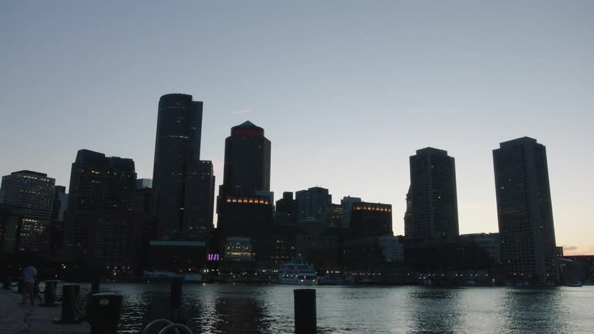 City skyline with tall buildings silhouetted against the sky at dusk