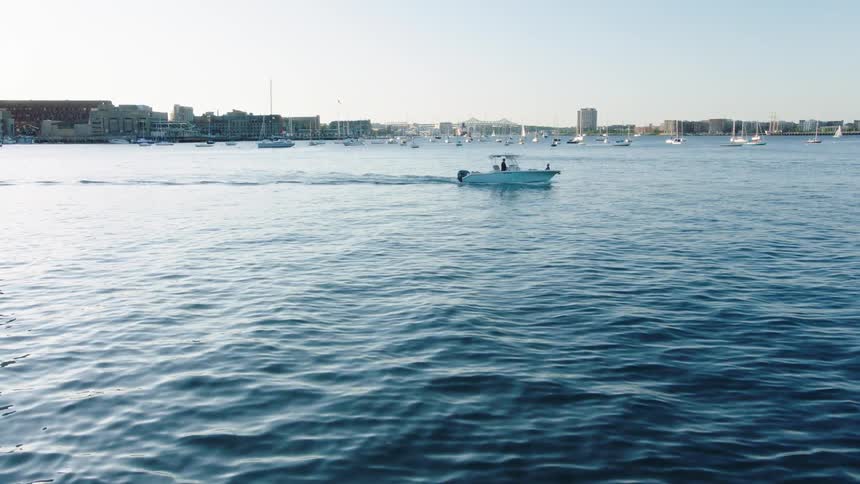 A boat travels across a bay bordering a metropolis on a sunny day
