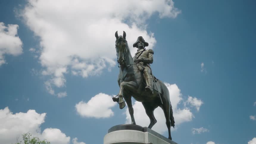 A statue of a man on a horse with a tree the sky and clouds in the background