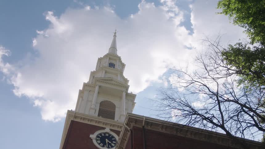 Looking up at a steeple and clock on a church