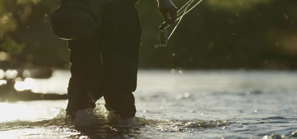 A man walks in the water as he fishes
