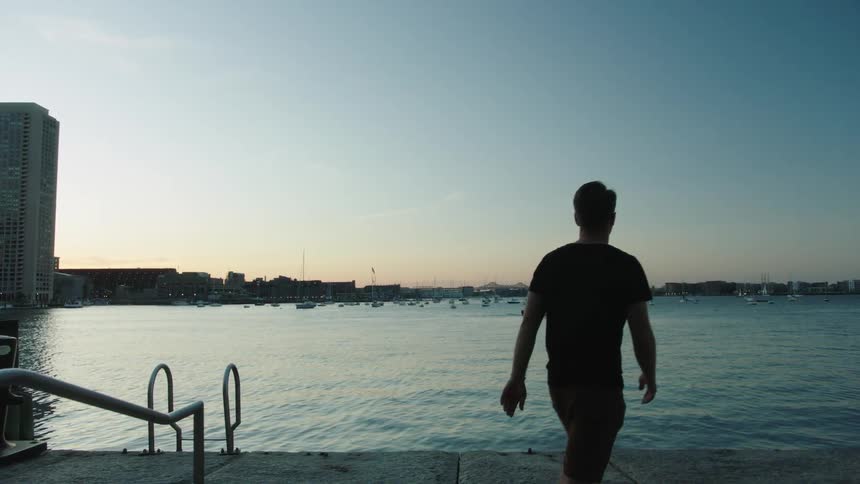 A man walks to a large platform on a pier next to a lake