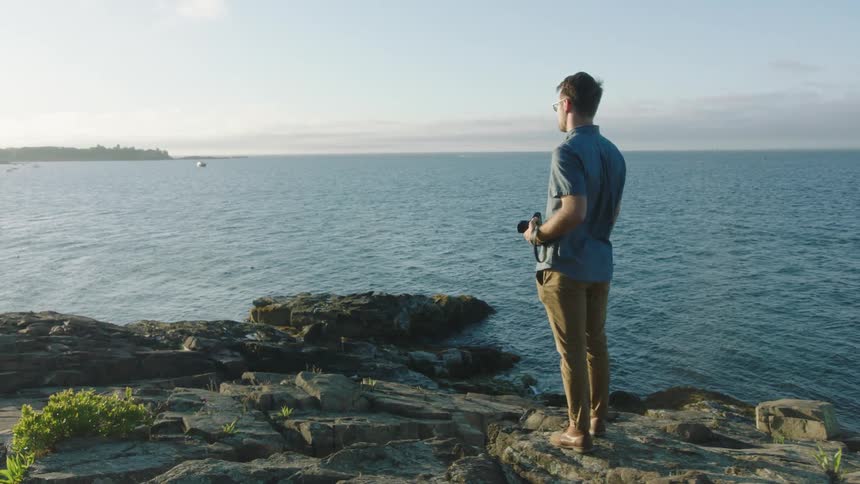 A man using a camera at the ocean