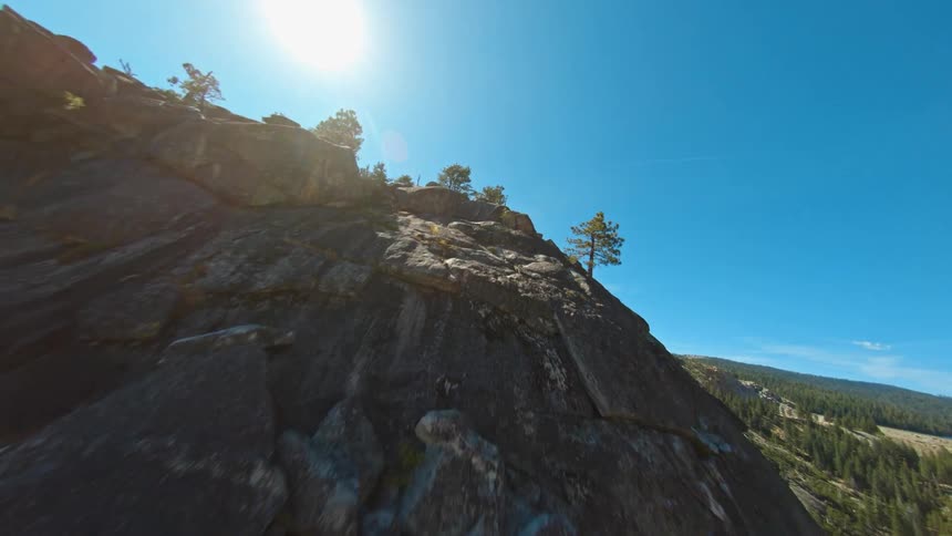 A cliff with plants and trees with the sky and clouds in the background