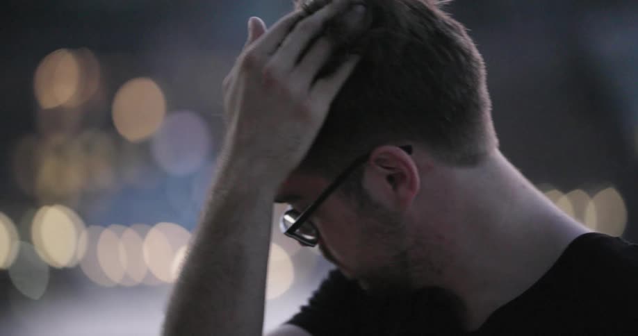 A man runs his hand through his hair as he looks down at his smart phone