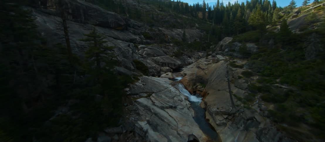 A river in a canyon with trees with the sky and clouds in the background
