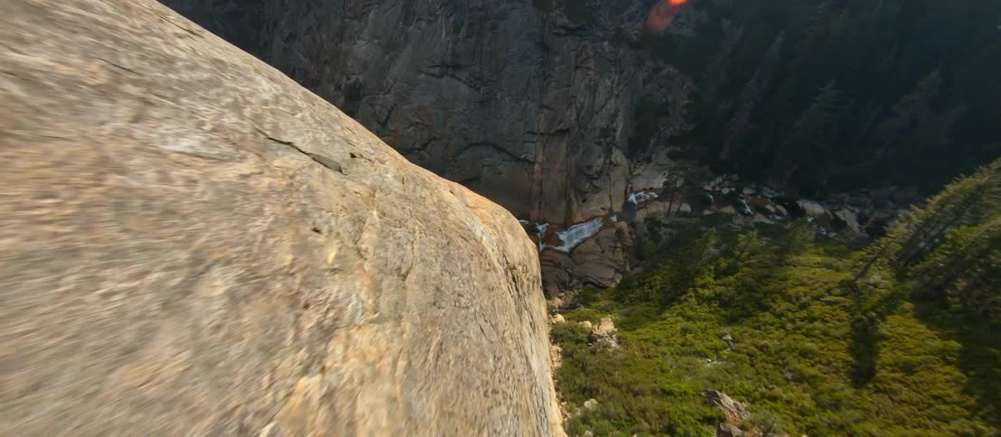 An aerial view of pine trees in a rocky mountain on a summer day