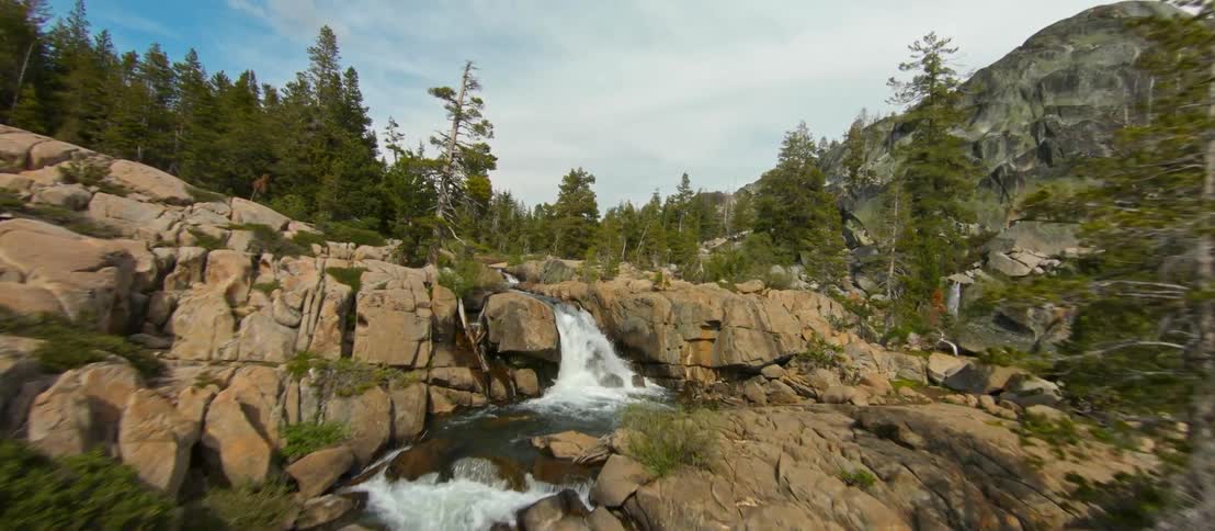 The river runs down the mountain full of trees