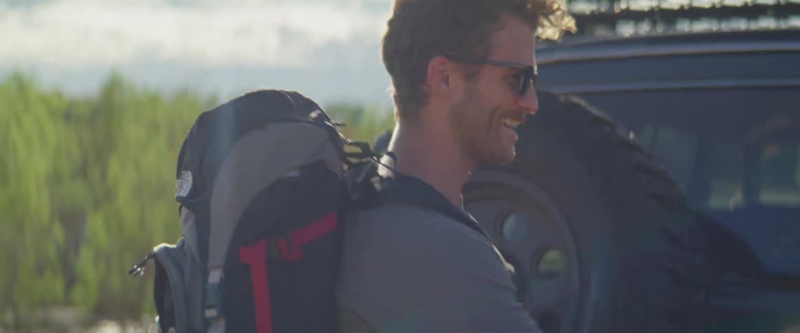 A male and female hiker close the back door of their vehicle as they prepare for a hike