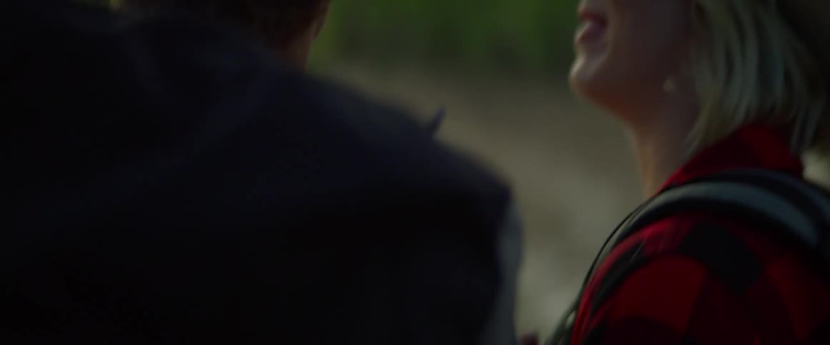 A woman with her hand on a mans shoulder laughs as they stand outside