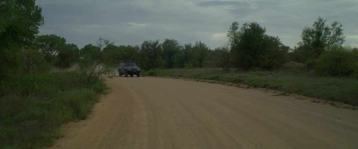 Pickup truck drives on a dirt road through the plains