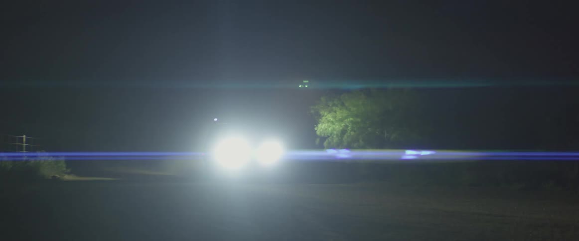 A car is driving down a road at night