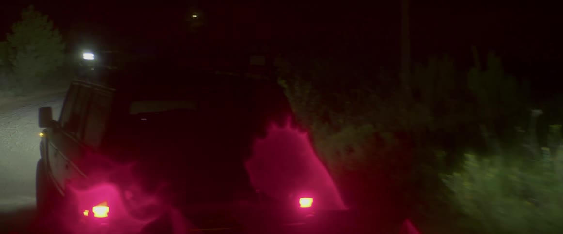 A car is driving on a road at night