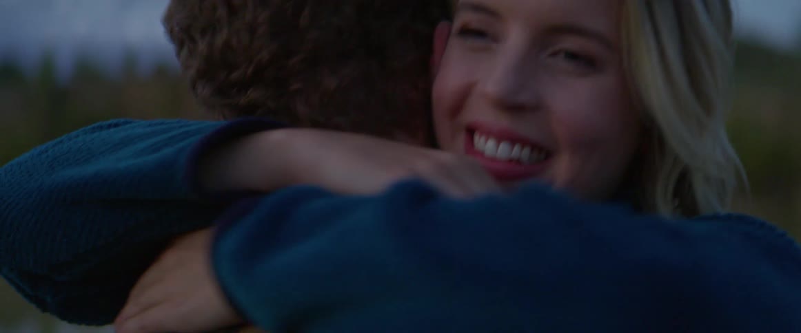 A woman laughs as she hugs a man