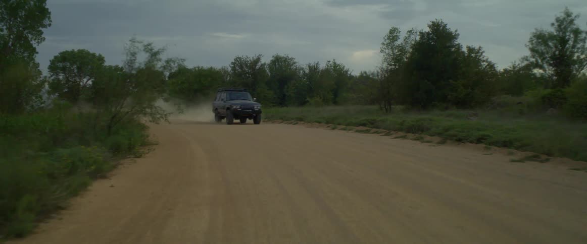 A car traveling on a rural dirt road on a summer day