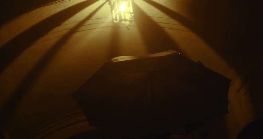 A man is walking at night with an umbrella