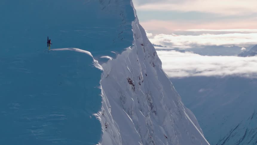 A skier stands on a mountain and looks out across the landscape