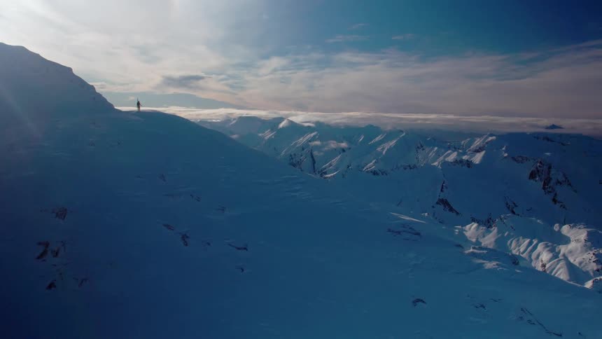 A person is standing at the top of the mountain ahead