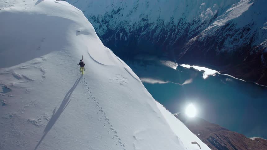 A mountaineer uses trekking poles to hike up a high mountain slope