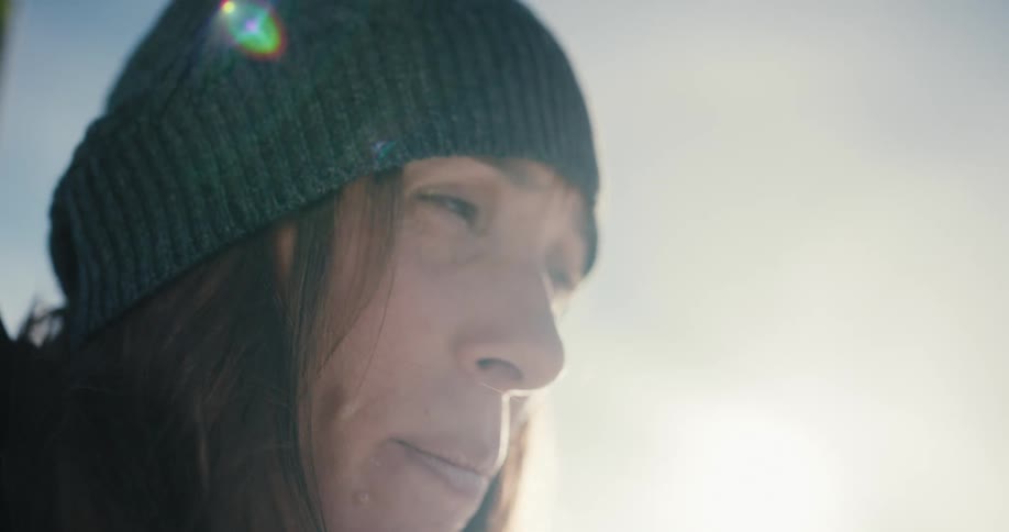 Side view of a woman with brown hair and a beanie under the sun