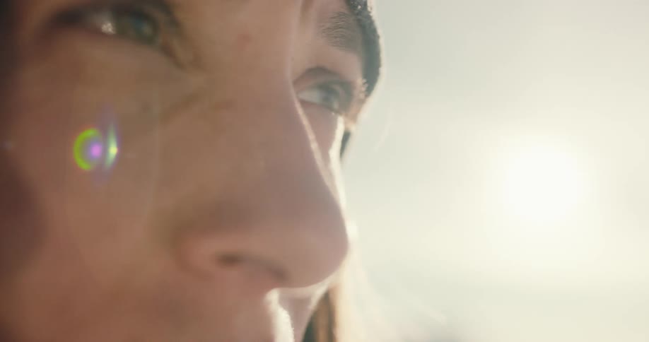 A woman standing outdoors lowers a pair of binoculars from her eyes