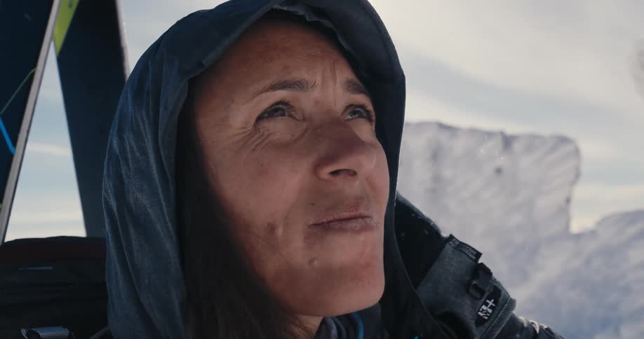 A woman is looking up at the sky as it snows