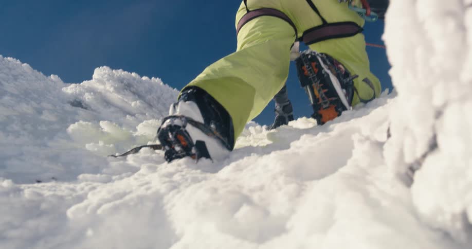 A man is climbing an icy and snowy mountain on a sunny day