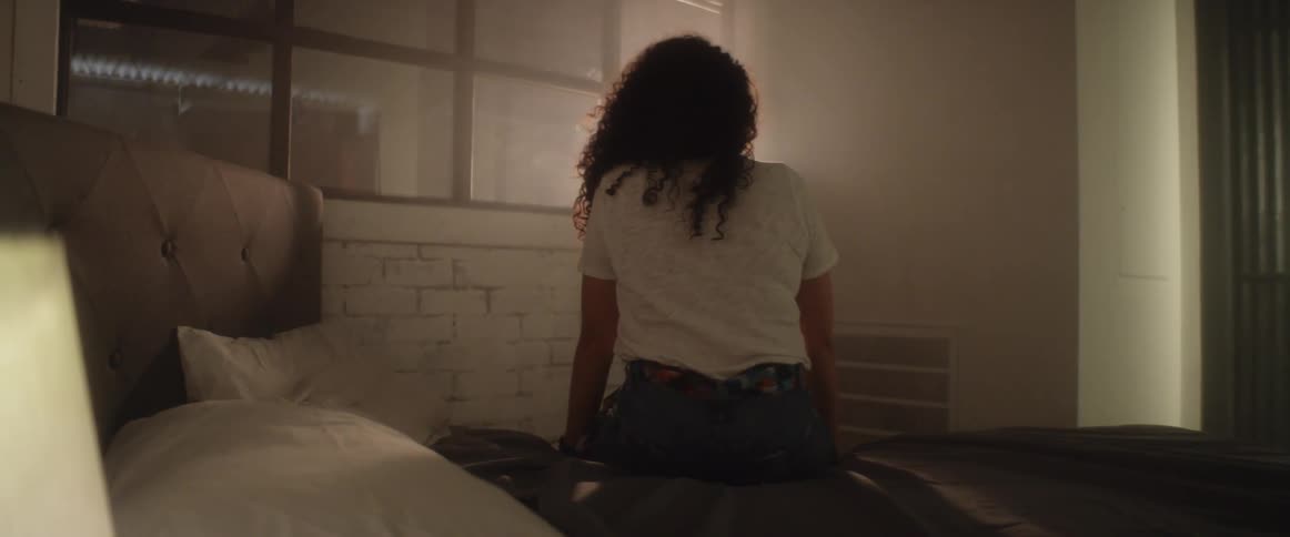A woman is sitting in a bedroom
