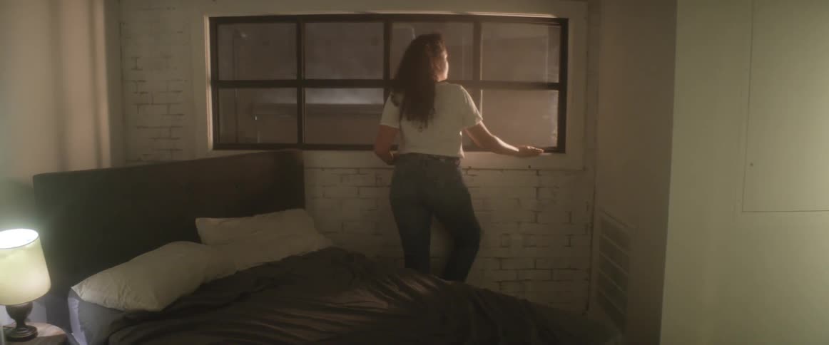 Woman looks out the window next to the bed on the bedroom at night